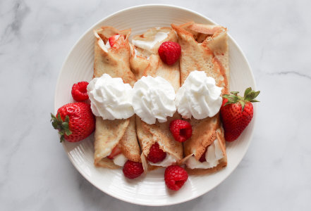 Plate of crepes with cream and berries